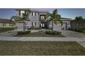 Elegant two-story home boasts a three-car garage and meticulous landscaping with lush palm trees at dusk at 3280 Juniper Springs St, Wesley Chapel, FL 33543