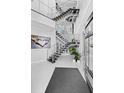 Bright foyer featuring a contemporary staircase with stainless steel railings, modern art, and high ceilings at 10100 Tarpon Dr, Treasure Island, FL 33706