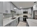 Modern kitchen with gray cabinets, stainless appliances, and mosaic tile backsplash at 1025 Apollo Beach Blvd # 1, Apollo Beach, FL 33572
