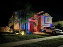 Striking two-story house illuminated with colorful lights, highlighting its architectural details and landscaping at 13856 Crest Lake Dr, Hudson, FL 34669