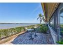 Waterfront patio area with brick pavers and a small table set with lush green landscaping, and water views at 19029 Us Highway 19 N # 17A, Clearwater, FL 33764