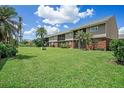 The exterior of the apartment building with a lush green lawn and palm trees on a sunny day at 200 Country Club Dr # 1001, Largo, FL 33771