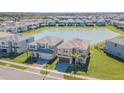 An aerial view of two houses situated by a lake with many other houses surrounding the area at 32684 Tamarind Grove Ln, Wesley Chapel, FL 33543