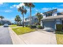 View of the townhouses with well-manicured lawns, palm trees, and a blue sky at 4238 Brentwood Park Cir, Tampa, FL 33624