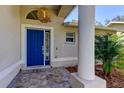 Inviting entryway featuring a vibrant blue door, decorative column, and lush landscaping at 4967 162Nd N Ave, Clearwater, FL 33760