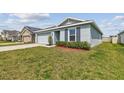 Well-maintained single-story home featuring green grass, a trimmed bush, and an attached two-car garage at 8034 Broad Pointe Dr, Zephyrhills, FL 33540