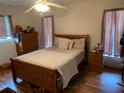 Bedroom features a wood bed frame, matching bedside table and dresser with hardwood floors at 9427 Wolcott Ln, Port Richey, FL 34668