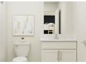 Bright bathroom featuring a white vanity with sink, toilet, and artistic wall decor at 13029 Ruby Gold Ct, Wimauma, FL 33598