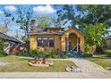 Quaint yellow home featuring a brick chimney, well-manicured lawn, and arched front porch at 3235 8Th N Ave, St Petersburg, FL 33713