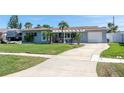 Charming single-story home featuring a well-manicured lawn, attached garage, and a welcoming covered entryway at 553 E Lake Dr, Largo, FL 33771