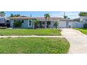 Well-kept single-story home with a green lawn, driveway, and a cozy, covered front porch area at 553 E Lake Dr, Largo, FL 33771
