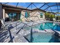 Inviting screened-in pool and spa with plenty of seating, a grill, and covered patio perfect for outdoor entertaining at 6104 Talon Preserve Dr, Nokomis, FL 34275
