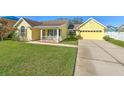 Inviting yellow home featuring a well-maintained lawn and an attached two-car garage at 6217 Evansbrook Dr, Zephyrhills, FL 33541