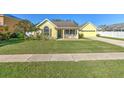 Lovely yellow home with front porch and lush green lawn on a sunny day at 6217 Evansbrook Dr, Zephyrhills, FL 33541