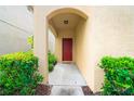 Covered entryway featuring a red front door framed by lush greenery at 9033 Aspen Hollow Pl, Riverview, FL 33578