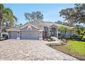 Charming single-story home featuring a three-car garage, brick driveway, and landscaped front yard at 10129 Paddock Oaks Dr, Riverview, FL 33569