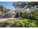 Charming single-story home featuring a three-car garage, brick driveway, and lush landscaped front yard at 10129 Paddock Oaks Dr, Riverview, FL 33569