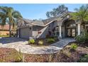 Charming single-story home featuring a three-car garage, brick driveway, and landscaped front yard at 10129 Paddock Oaks Dr, Riverview, FL 33569