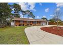 Attractive one-story home with lush landscaping and a long, curved driveway at 1290 Michigan Blvd, Dunedin, FL 34698