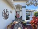 Inviting front entry with tiled walkway, decorative foliage, and charming accents at 18504 Water Lily Ln, Hudson, FL 34667