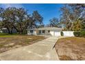 A well-maintained single story home with a concrete driveway and a front lawn, surrounded by mature trees at 2050 Nigels Dr, Dunedin, FL 34698