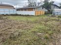 Vacant lot enclosed by a white and brown fence with buildings in the background at 4104 W Osborne Ave, Tampa, FL 33614