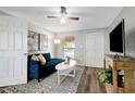 Cozy living room featuring hardwood floors, a plush blue couch, and a modern ceiling fan at 1032 Jadewood Ave, Clearwater, FL 33759