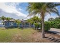 Inviting single-story home with a covered porch, a cozy porch swing, mature palms, and a well-maintained lawn at 10754 111Th N Pl, Largo, FL 33778