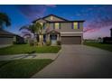 Charming two-story home at dusk featuring a well-manicured lawn, a wide driveway, and a two-car garage at 13006 Tidal Flats Loop, Riverview, FL 33579