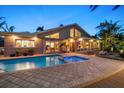 A backyard pool and attached hot tub under the lights of dusk and the shadow of the house behind it at 447 22Nd St, Belleair Beach, FL 33786