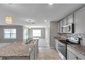 A modern kitchen featuring granite countertops and stainless steel appliances open to the living space at 7608 Broad Pointe Dr, Zephyrhills, FL 33540
