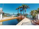 Backyard pool area with a waterfall feature leading to a serene waterfront view and dock at 15417 2Nd E St, Madeira Beach, FL 33708