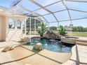 Resort-style screened pool features rock waterfall, tropical plants, fire pit and golf course view at 18111 Diamond Cove Ct, Tampa, FL 33647