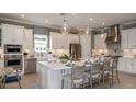 Modern kitchen features white cabinets, stainless steel appliances, a central island, and elegant pendant lighting at 29444 Toricelli Rd, Wesley Chapel, FL 33543