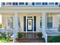 Inviting front porch features a ceiling fan, decorative door, wood flooring, and cozy seating for relaxing outdoors at 310 Manns Harbor Dr, Apollo Beach, FL 33572