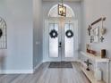 Elegant entryway featuring double doors with frosted glass, wood-look tile flooring, and stylish decorations at 3537 Valencia Cove Court, Land O Lakes, FL 34639