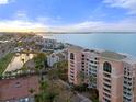 Aerial view of the luxurious waterfront condo complex with tennis court, pristine landscaping, and serene water views at 4951 Bacopa S Ln # 801, St Petersburg, FL 33715