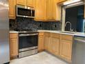 Bright kitchen features stainless steel appliances, wooden cabinets, tile backsplash, and solid surface countertops at 6815 Dali Ave # F101, Land O Lakes, FL 34637