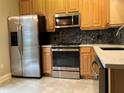 Bright kitchen features stainless steel appliances, wooden cabinets, tile backsplash, and solid surface countertops at 6815 Dali Ave # F101, Land O Lakes, FL 34637