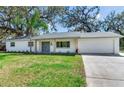 Landscaped front yard of a charming white home with a gray roof and a two-car garage at 303 Suzette Dr, Brandon, FL 33511