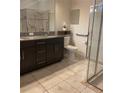 Bathroom featuring dark wood vanity with granite countertop, a large mirror, and a walk-in shower with glass doors at 11648 Palmetto Pine St, Riverview, FL 33569