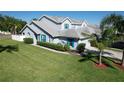 Exterior of a light blue two-story home with bright turquoise shutters and a meticulously maintained, expansive green lawn at 284 Hemingway Dr, Oldsmar, FL 34677
