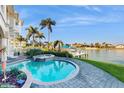 Backyard pool with a spa, waterfront view, and mature palm trees at 750 123Rd Ave, Treasure Island, FL 33706