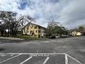 Condo exterior featuring a parking lot and mature trees against a cloudy sky at 8550 Shadblow Ct # 2, Port Richey, FL 34668