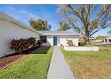 Close-up of a home's entrance with a walkway, blue front door, and tidy landscaping at 1022 Mctavish Way, Palm Harbor, FL 34684