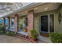 Welcoming front entrance with brick support columns, green exterior walls, black door, and neat landscaping at 3111 Teal Ter, Safety Harbor, FL 34695
