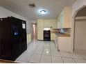 Kitchen featuring white tile flooring, black appliances, and wood trim at 5439 County Road 579, Seffner, FL 33584