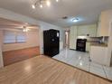 A bright kitchen featuring white tile flooring, black appliances, wood trim, and an adjacent dining area at 5439 County Road 579, Seffner, FL 33584