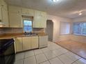 A well-lit kitchen featuring white tile flooring, laminate counters, stainless steel sink, and an adjacent dining area at 5439 579 Hwy, Seffner, FL 33584