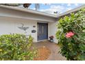 Inviting front entrance with a blue door, heron artwork, and lush landscaping with blooming hibiscus at 8000 13Th S Ave, St Petersburg, FL 33707